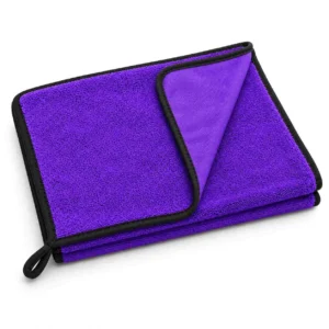 Purple microfibre cleaning towel with one corner turned back, black bound edges and a hanging loop on a white background.